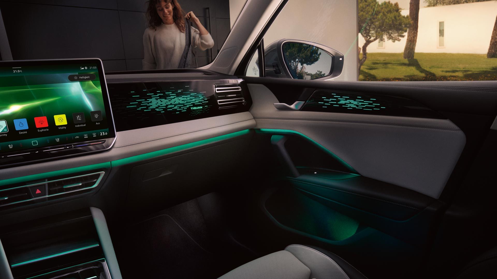 Vedere interioară a modelului VW Tiguan noaptea, afișajul color prezintă setările iluminării ambientale opționale, habitaclul este iluminat în verde.