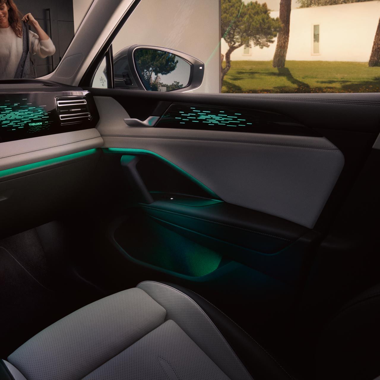 Vedere interioară a modelului VW Tiguan noaptea, afișajul color prezintă setările iluminării ambientale opționale, habitaclul este iluminat în verde.