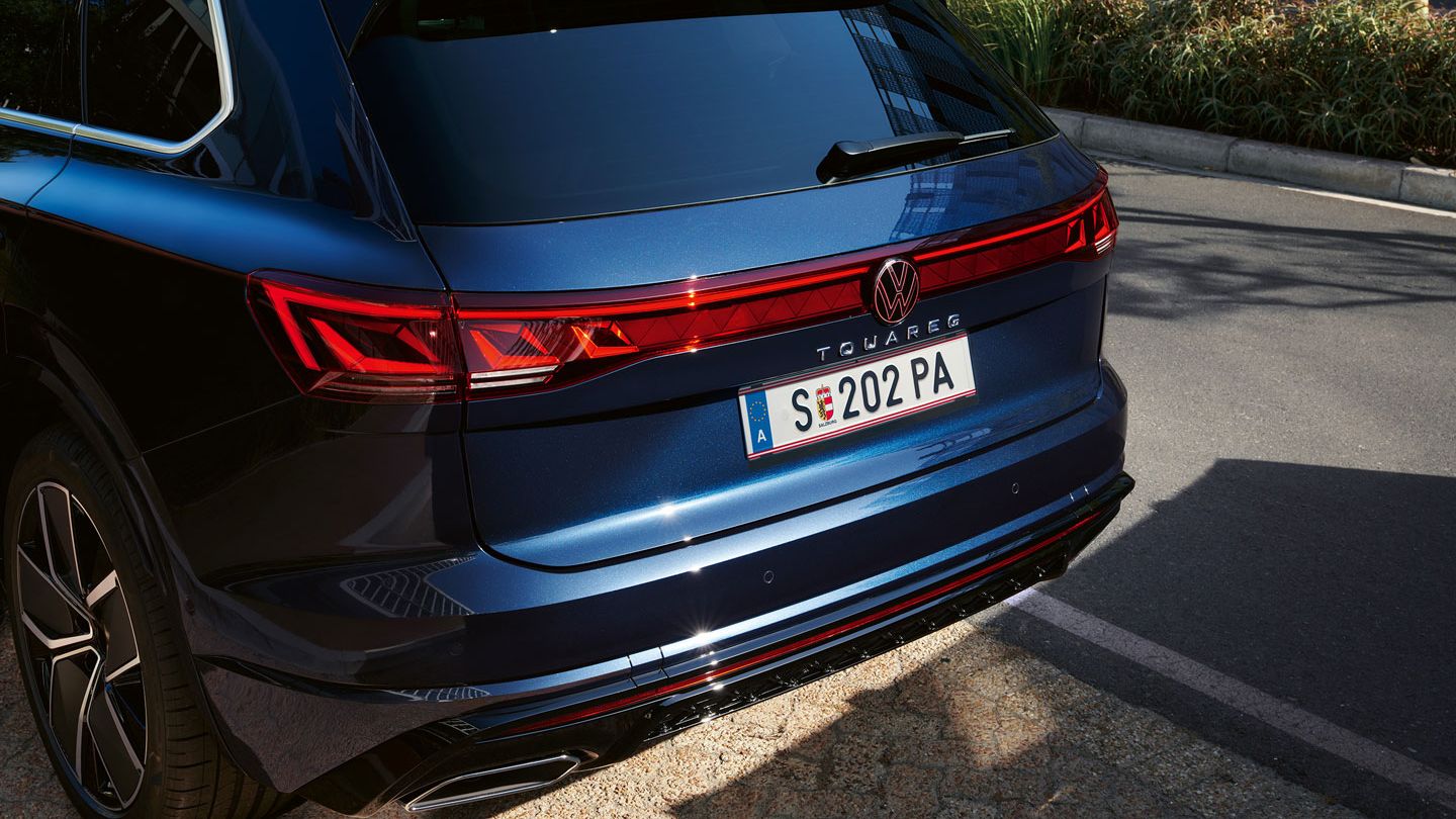 Vedere a părții din spate a unui VW Touareg R-Line cu lămpi spate cu leduri, bandă luminoasă și logo VW iluminat.