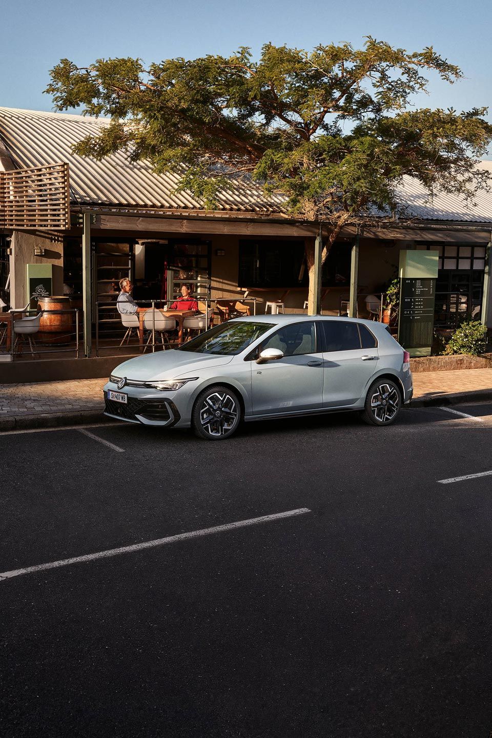 Un Golf R-Line alb parchează lateral în fața unui restaurant.