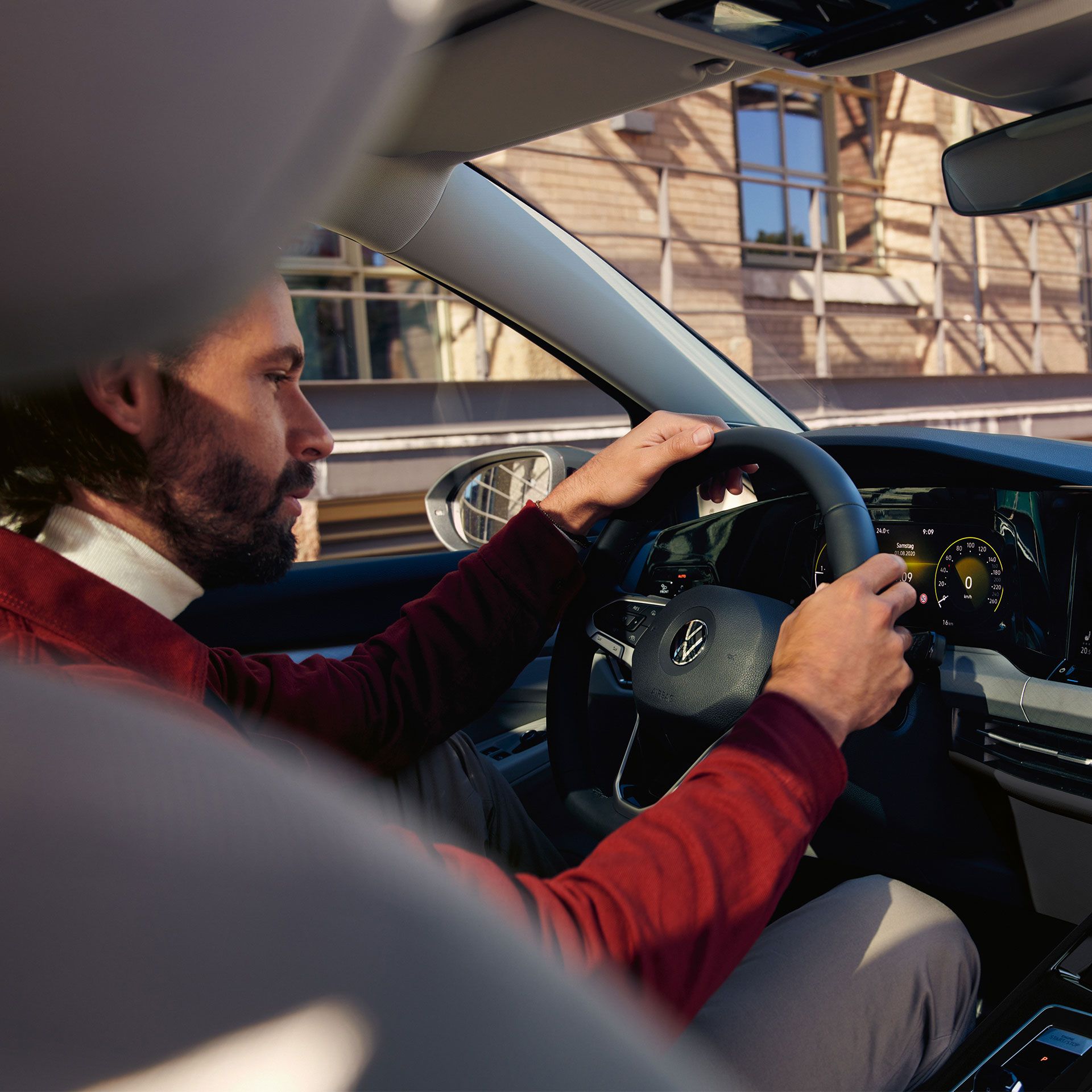 Mann sitzt im Auto mit den Händen am Lenkrad