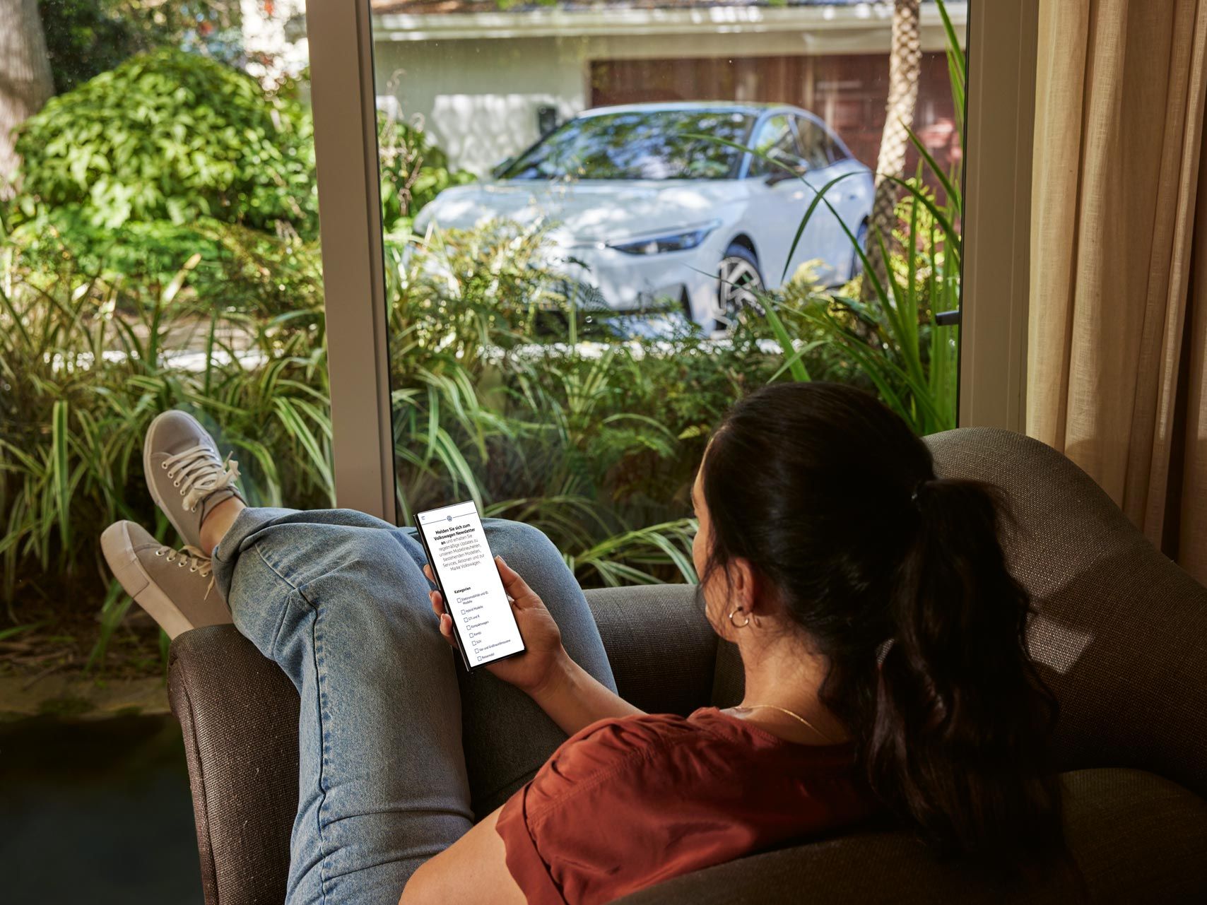 Frau sitzt gemütlich auf der Couch und liest den VW Österreich Newsletter