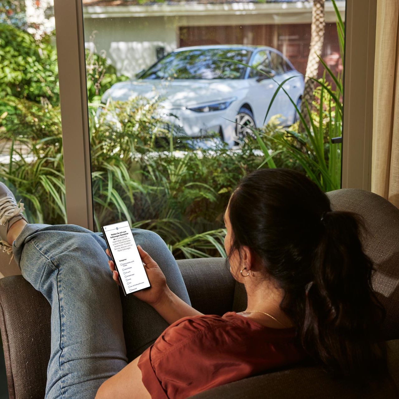 Frau sitzt gemütlich auf der Couch und liest den VW Österreich Newsletter